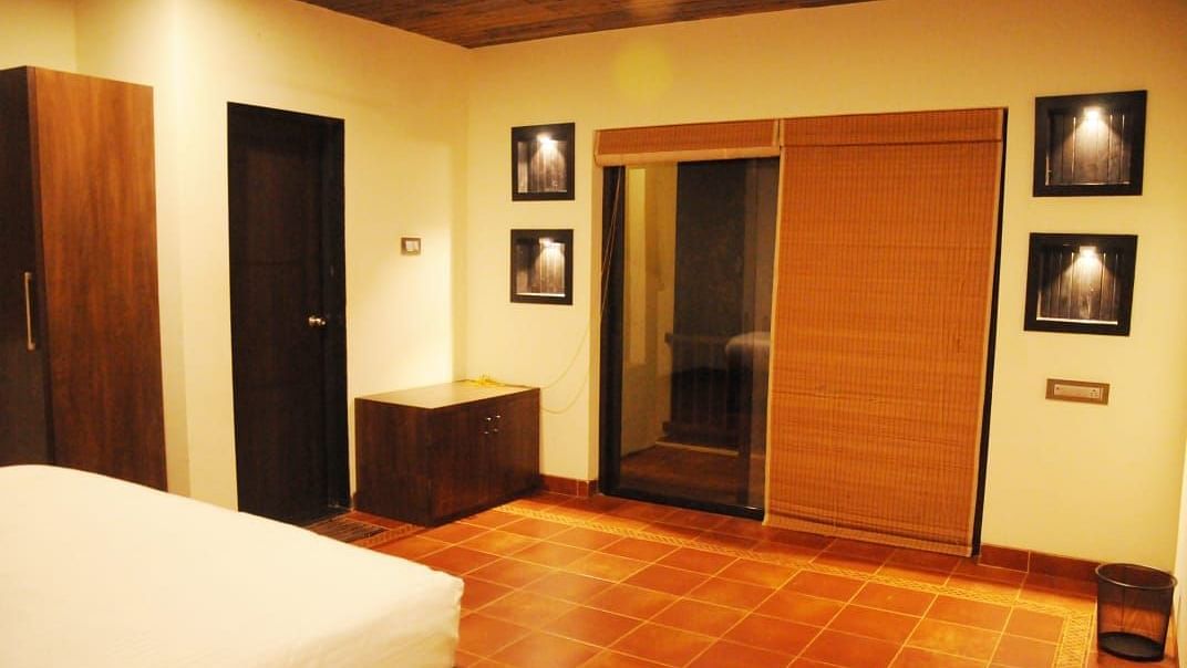 A room with a white bed, dark wood furniture, framed pictures on the wall, and a sliding door with a wooden panel.