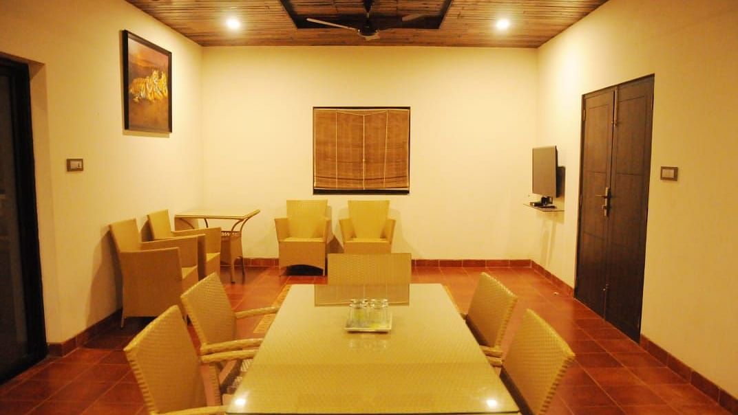 A dining room with a long wooden table, tan chairs, and framed artwork on the walls.