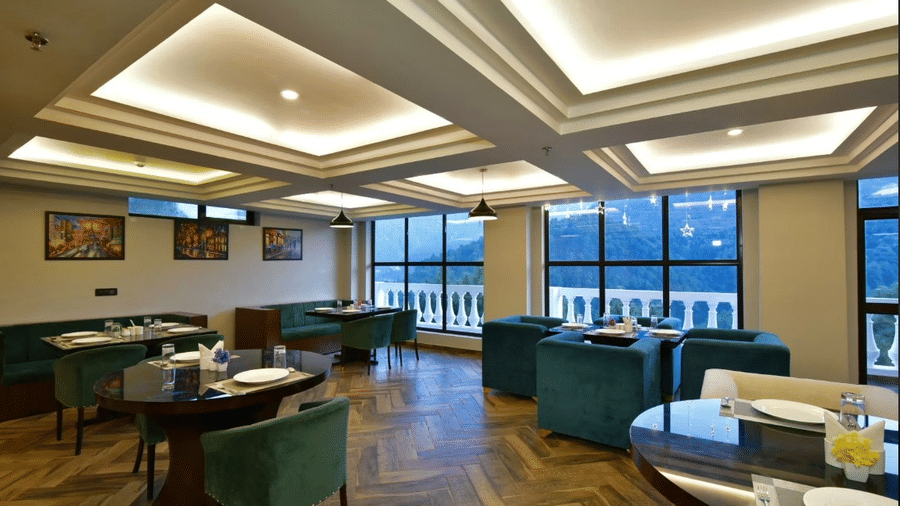 Claret Inn, Dalhousie - Seating area with green chairs, tables, ceiling lights, and wall art.
