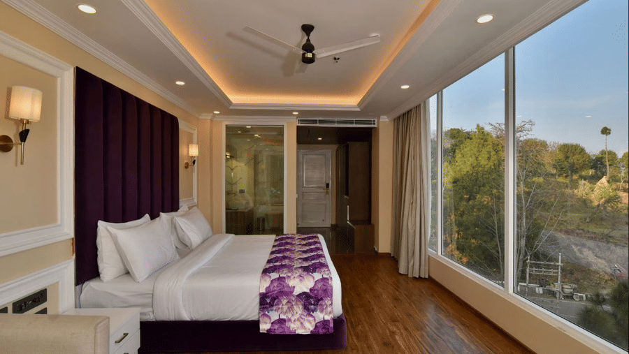 Elegant hotel rooms with balcony in Dalhousie with large windows, cosy bedding, and warm ceiling lights at Claret Inn, Dalhousie.