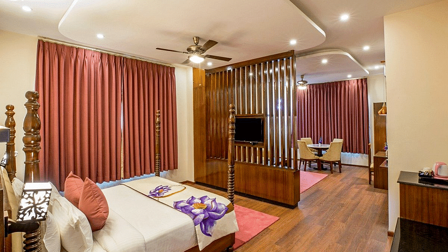Corner view angle of the Suite at Regenta Inn DLS with a wooden partition in the middle with a television mounted over it.