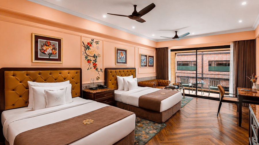 An Executive Twin Bed Room at MAYFAIR Bay Resort, Paradeep, featuring 2 beds, ceiling fans, wooden flooring and a seating area.