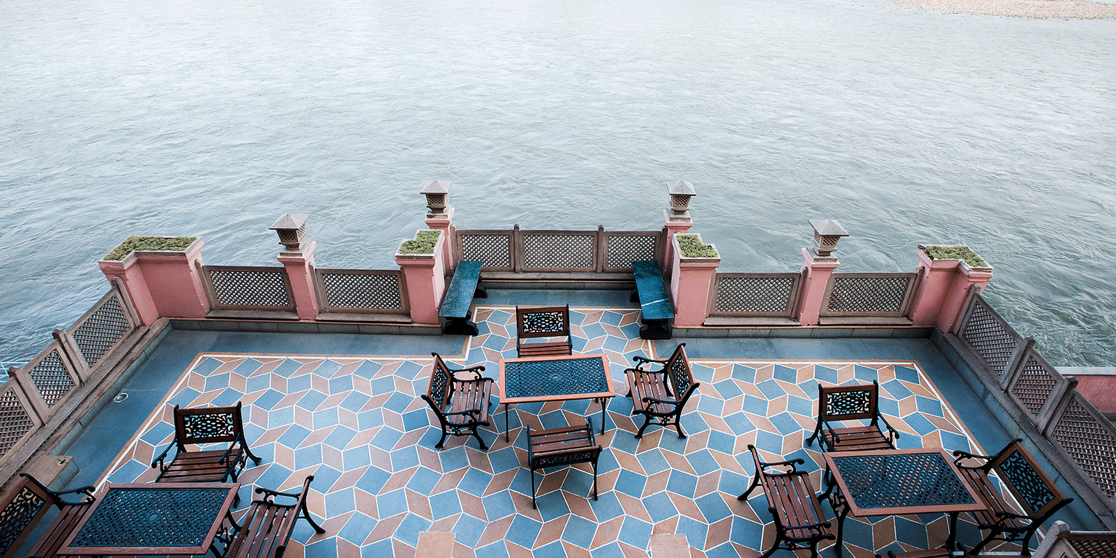 An open terrace dining space at Haveli Hari Ganga in Haridwar offers stunning views of the water body, providing a serene setting for guests to enjoy their meals while surrounded by the beauty of nature.