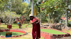 Guest enjoying mini golf at Fantasy Golf Resort, Bangalore surrounded by lush greenery.