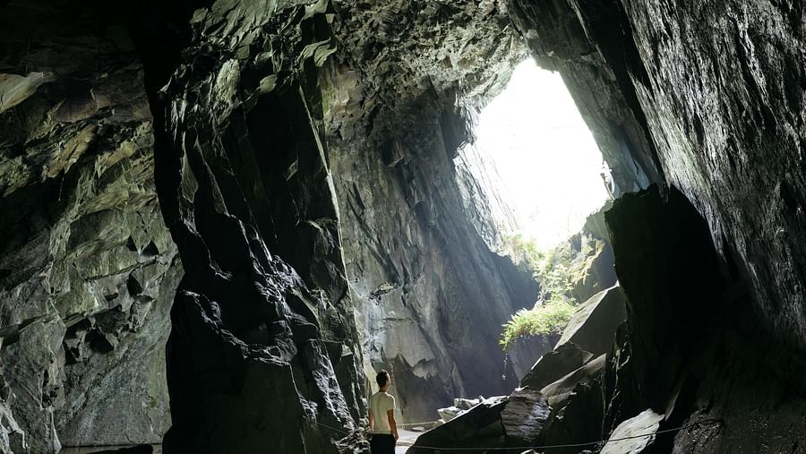 image of a man standing inside a cave with plenty of natural sun light falling inside it