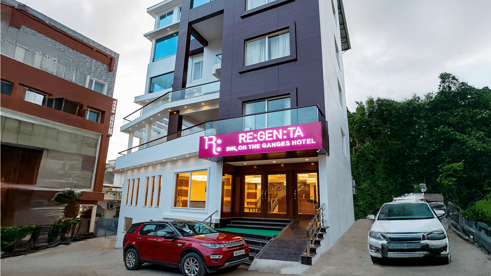 A wind angle shot of Regenta Inn DLS with a lush green hilly region in the background.