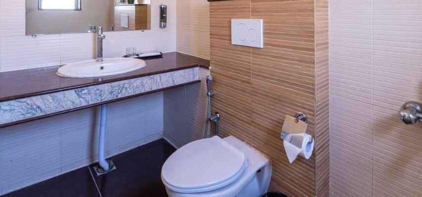 A clean and modern bathroom features a basin, mirror, and toilet, ensuring comfort and convenience at Lords Midtown Suites.