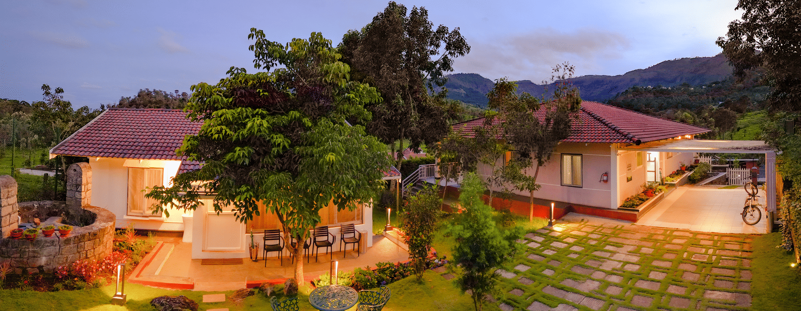 Cottages with tiled roofs, garden lawn and hills at Ibex Resorts, Kotagiri.