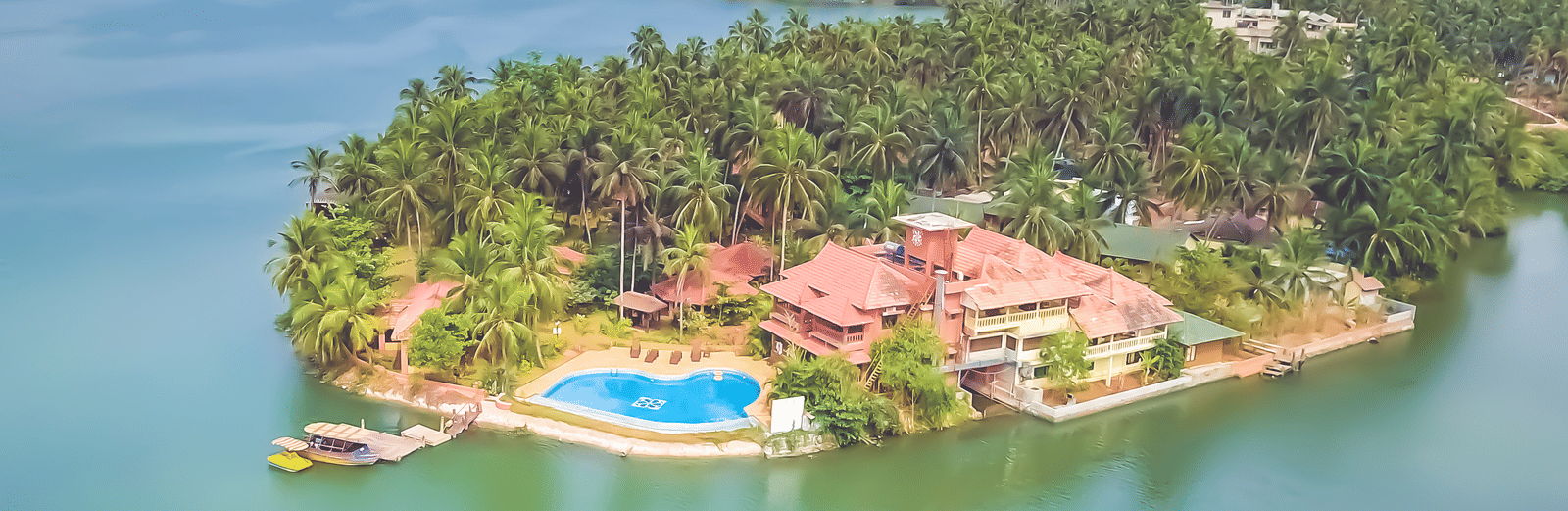 Aerial view of Paradise Lagoon Resort, Udupi, featuring a pool and water all around.