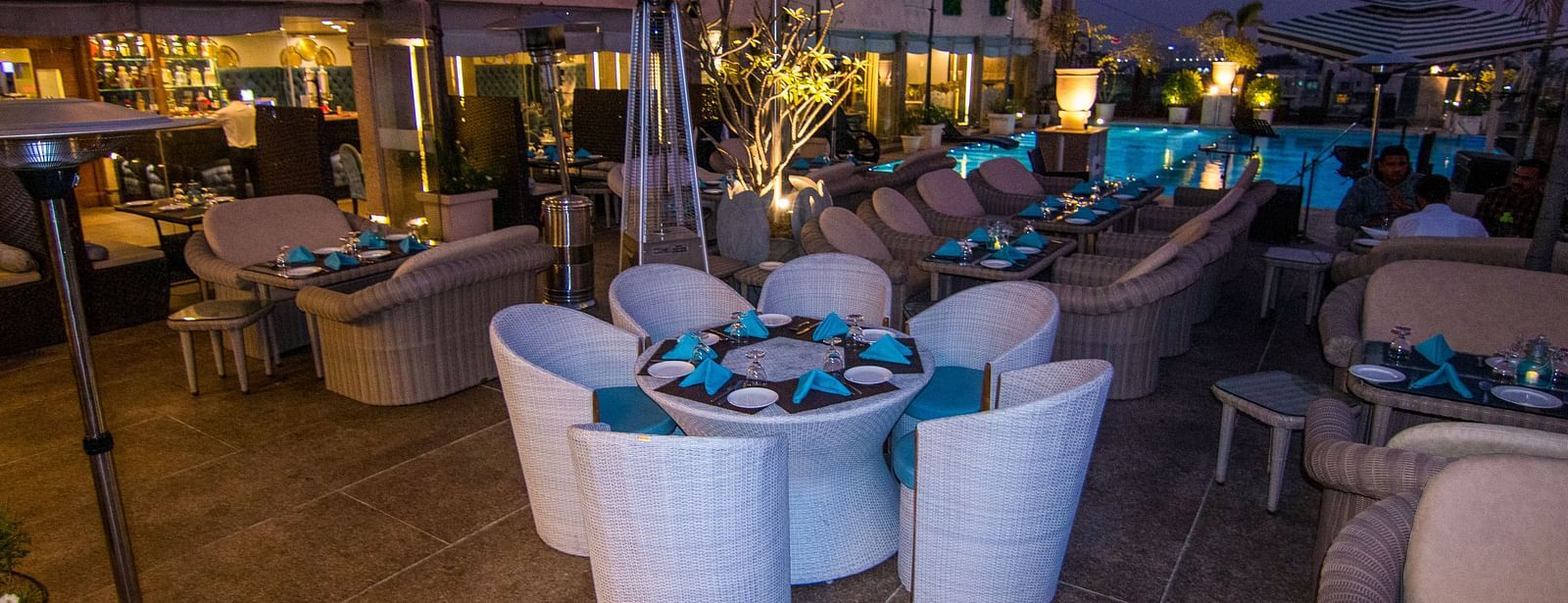 A eating area with white chairs around a small, round table with a blue centrepiece at Hotel Ashok Nagpur.