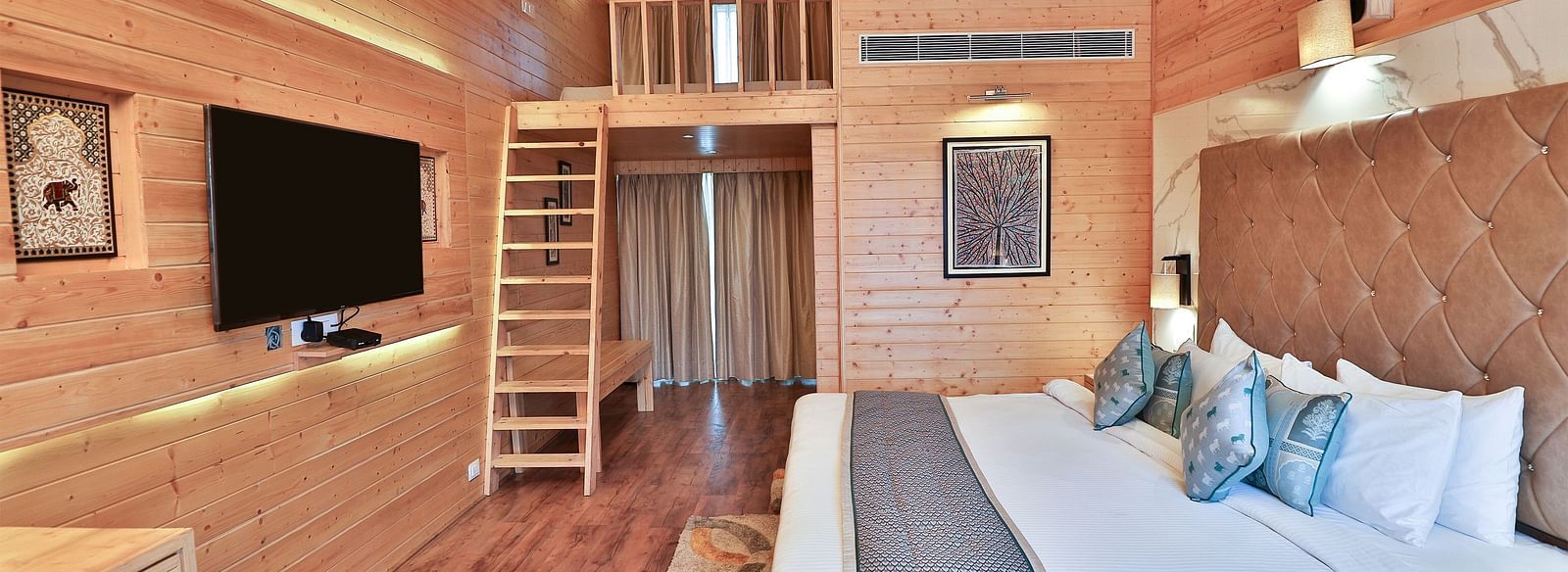 A cosy room with a plush bed, pillows and warm lighting. A ladder leads to a loft area. - Bamboo Saa Resort & Spa, Udaipur