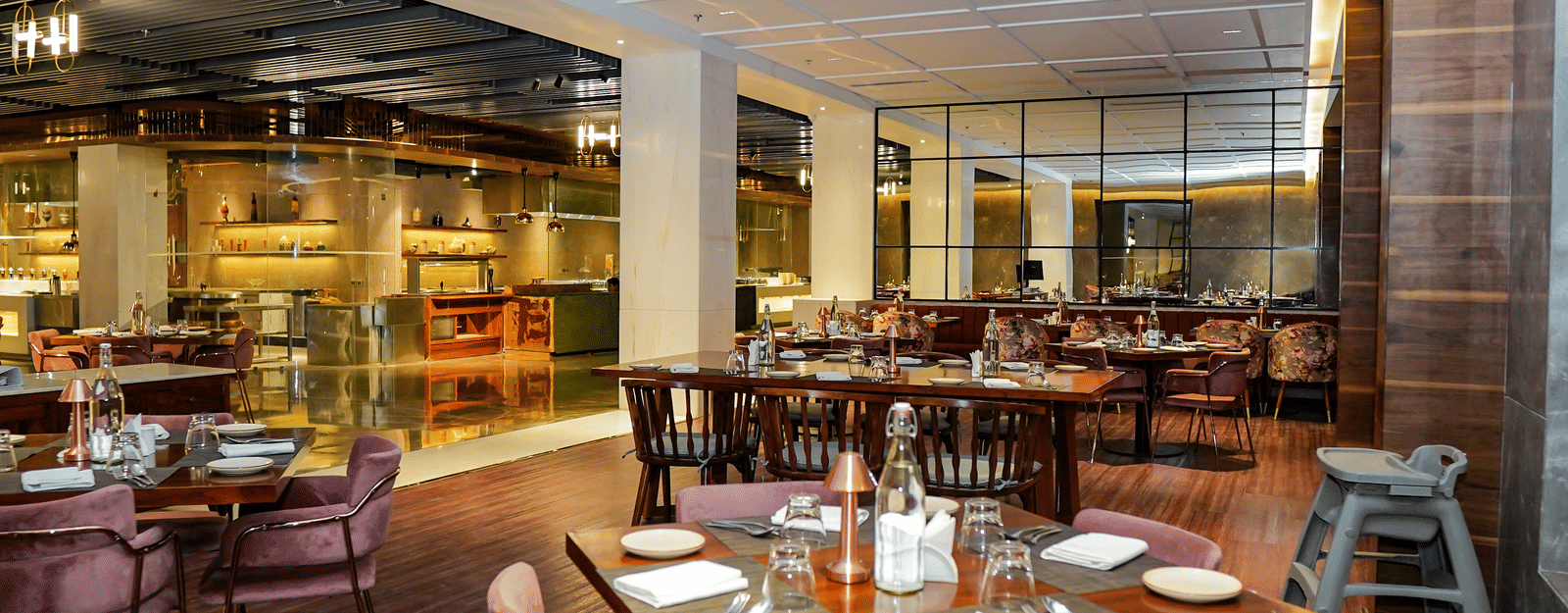 A bright, spacious fine dining restaurant with plush purple chairs and a high chair at Pushkara Resort & Spa.