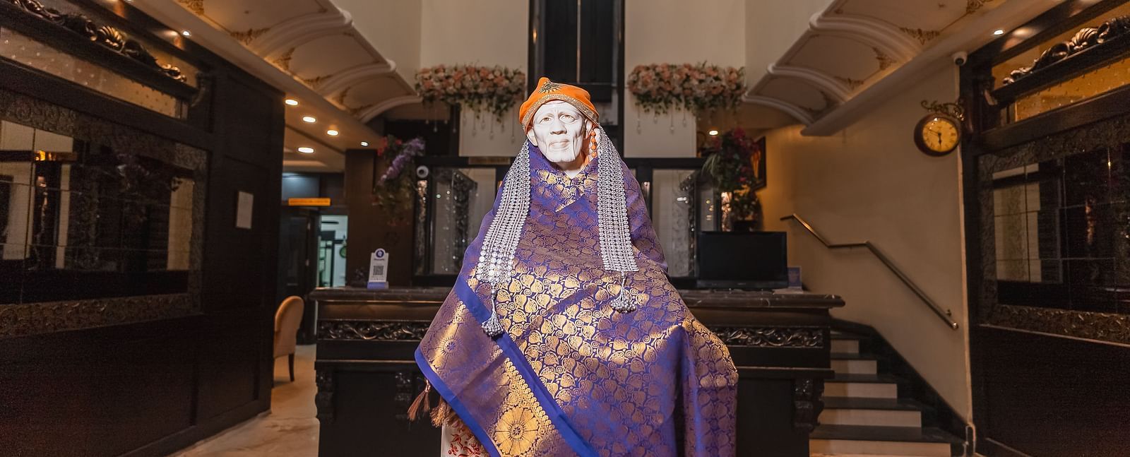 The statue of Sai Baba draped in fabric is positioned in the lobby at Hotel Ashok Nagpur.