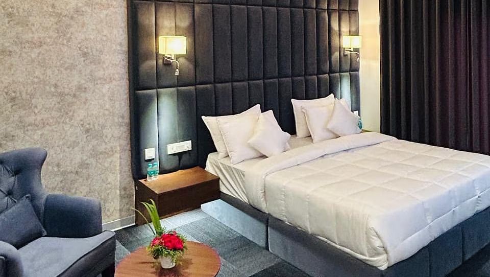 image of the premium room showcasing a common seating area and a plush double bed at Eminence The Corbett