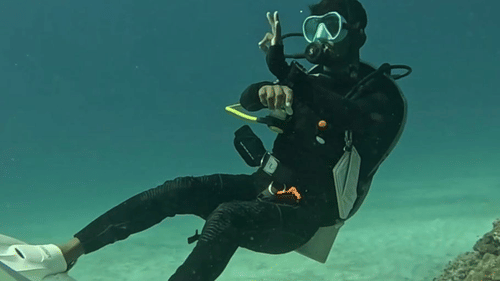 Single scuba diver underwater near sandy seabed practicing buoyancy control or diving skills.