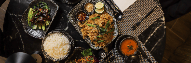 Table spread with plates and bowls containing rice, vegetables, curries, and sauces at Asiatic Rooftop Bar and Restaurant.