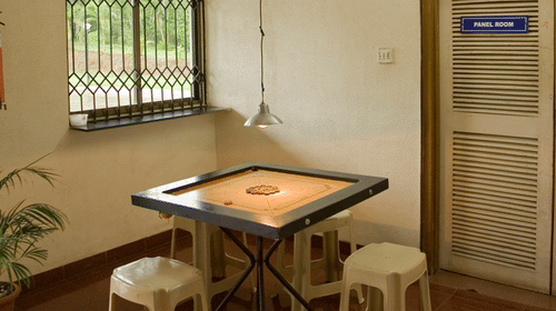 carrom board with plastic chairs next to it inside the Play Room - VITS Kamats Resort, Silvassa