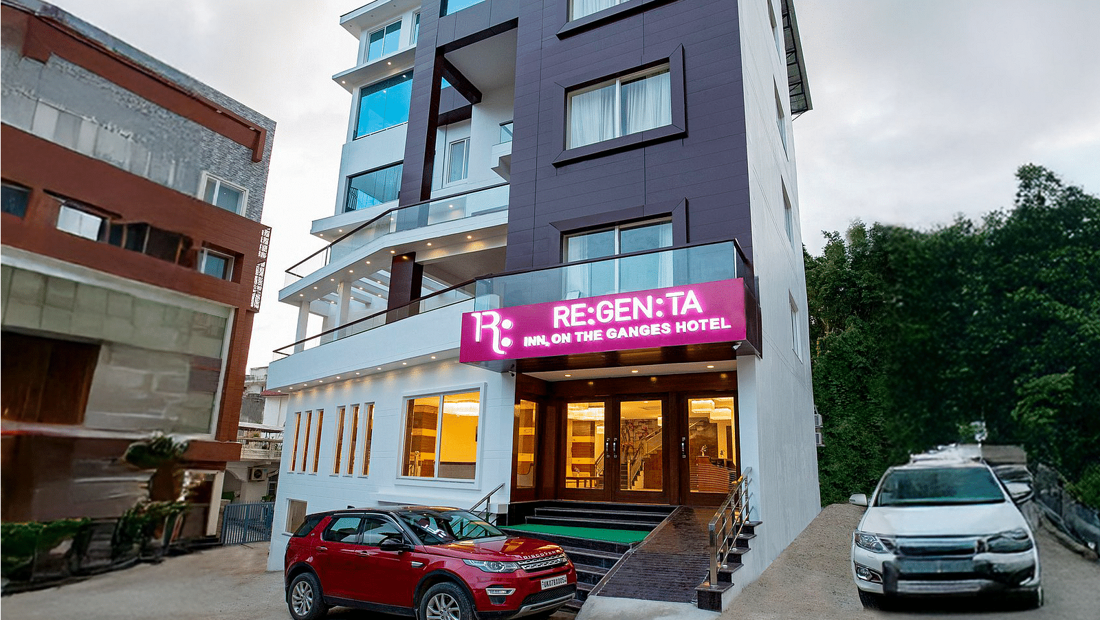 A wind angle shot of Regenta Inn DLS with a lush green hilly region in the background.