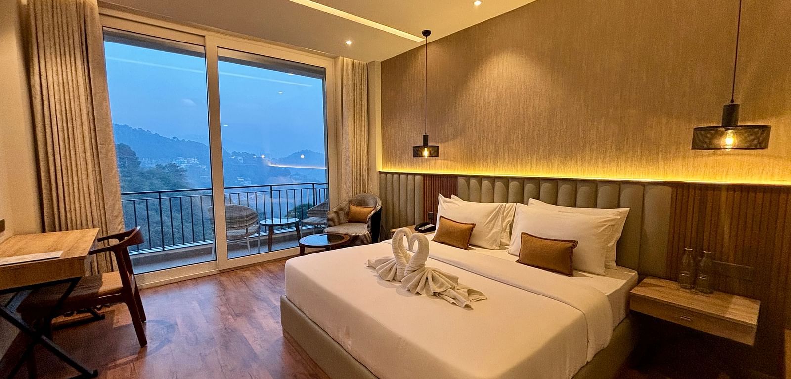 Elegant bedroom with large windows, wooden accents, and a scenic balcony view – ARNISA Boutique Hotel