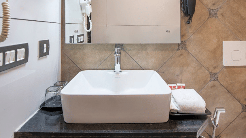 A well-lit sink area of a hotel room in Lords Inn Jamnagar with a mirror 