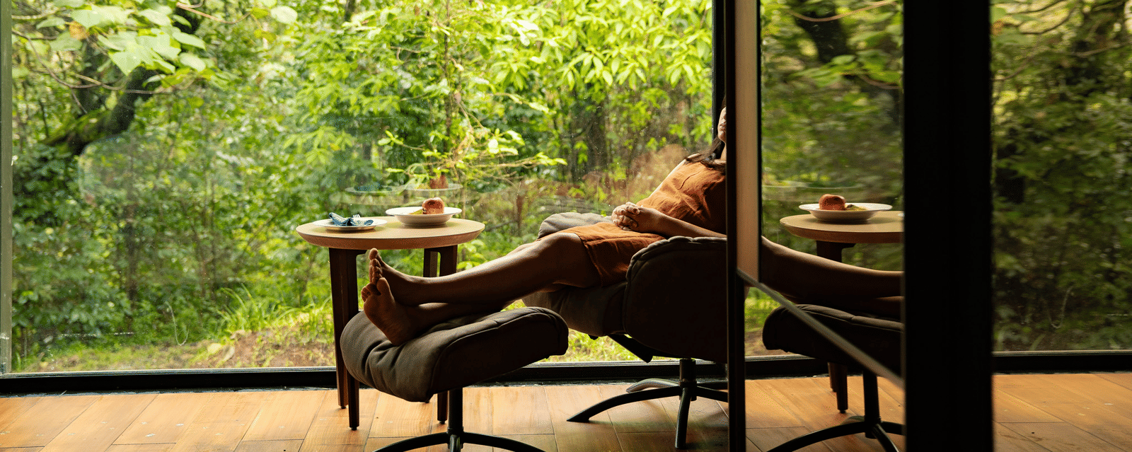 A person lounging in a balcony overlooking the forest at Stanley Leisure with a coffee table set up.