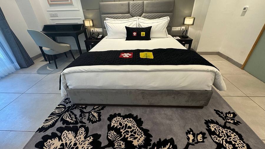 an image of a deluxe room with a designed carpet and a grey headboard at Mastiff Select Mandavya Dharamkot, McLeodganj