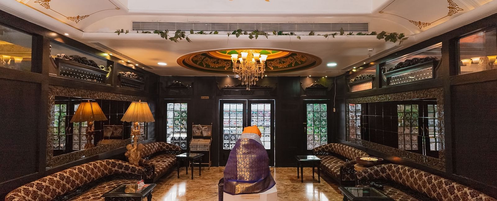 Lobby of Hotel Ashok Nagpur featuring a seating area with sofas and tables, and a wooden structure.