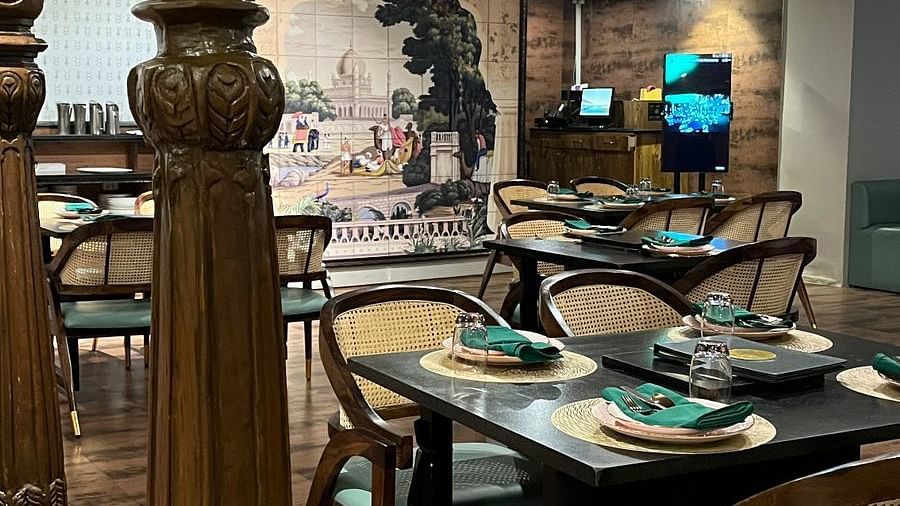Elegant restaurant interior featuring set tables with place settings, ornate columns, and a large mural on the back wall - Astra Hotels & Suites, Spice Garden Layout