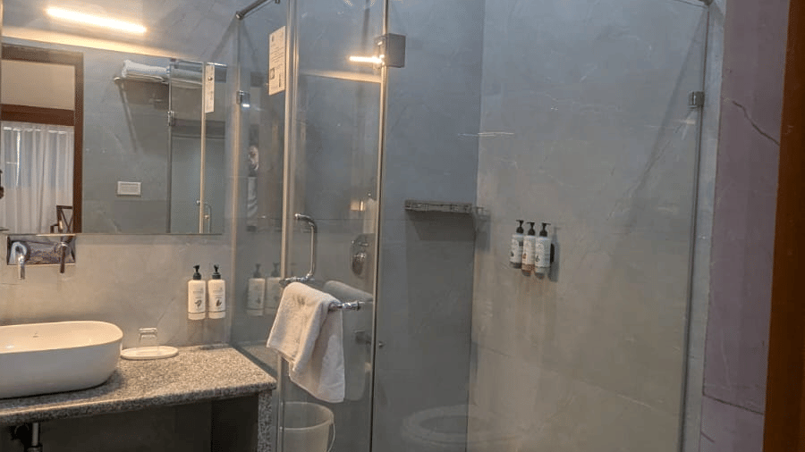 A Family Room's bathroom with glass shower enclosure, tiles, and sleek fixtures. A countertoModern bathroom with glass shower enclosure, tiles, and sleek fixtures. A countertop holds a sink, mirror, and toiletries, under warm lighting at  Bamboo Saa Sunrri