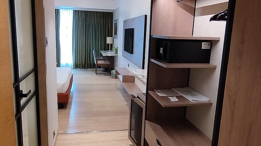 A view from the door way of an executive room in Mirage Hotel, featuring a wooden wardrobe area with a digital safe, and the entertainment unit.