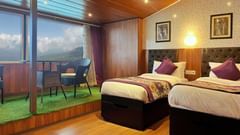 Attic Room at Mount Amara Hotel & Spa featuring twin beds, bedside table, lamps, wooden ceiling with lights, and a balconyattached.