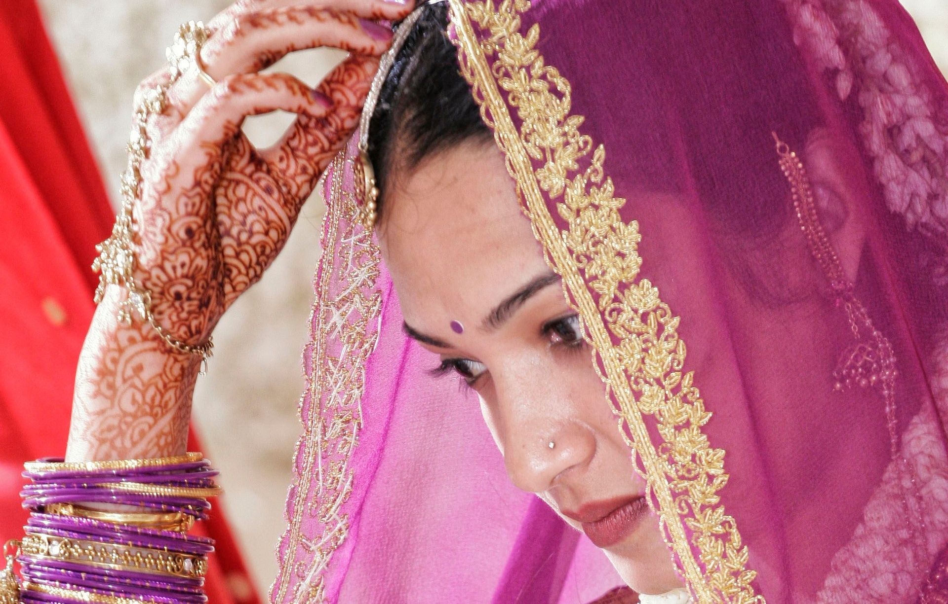 Indian bride adjusting her veil, hands with mehndi.