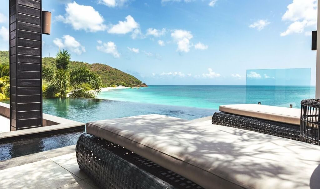 Infinity pool overlooking turquoise waters and green hills at Tamarind Hills Antigua – Resort & Villas