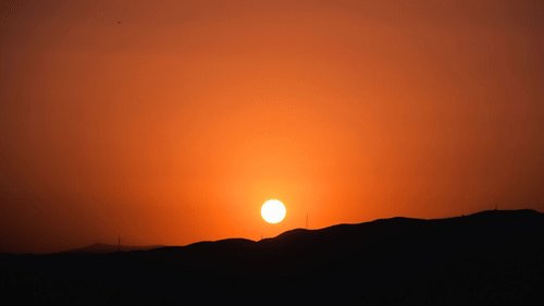 A stunning sunset casting an orange glow over rolling hills.