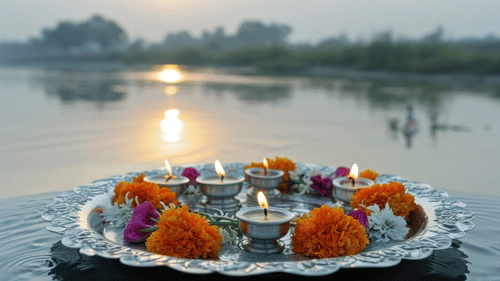 A traditional Indian offering with flowers and a diya floating on a pond at sunset