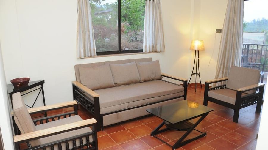A living room with a beige sofa, two armchairs, a coffee table, and a window with a view.