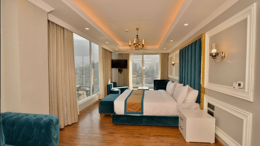 Claret Inn, Dalhousie - Room with a bed, curtains, blue bench, chandelier, and large windows.