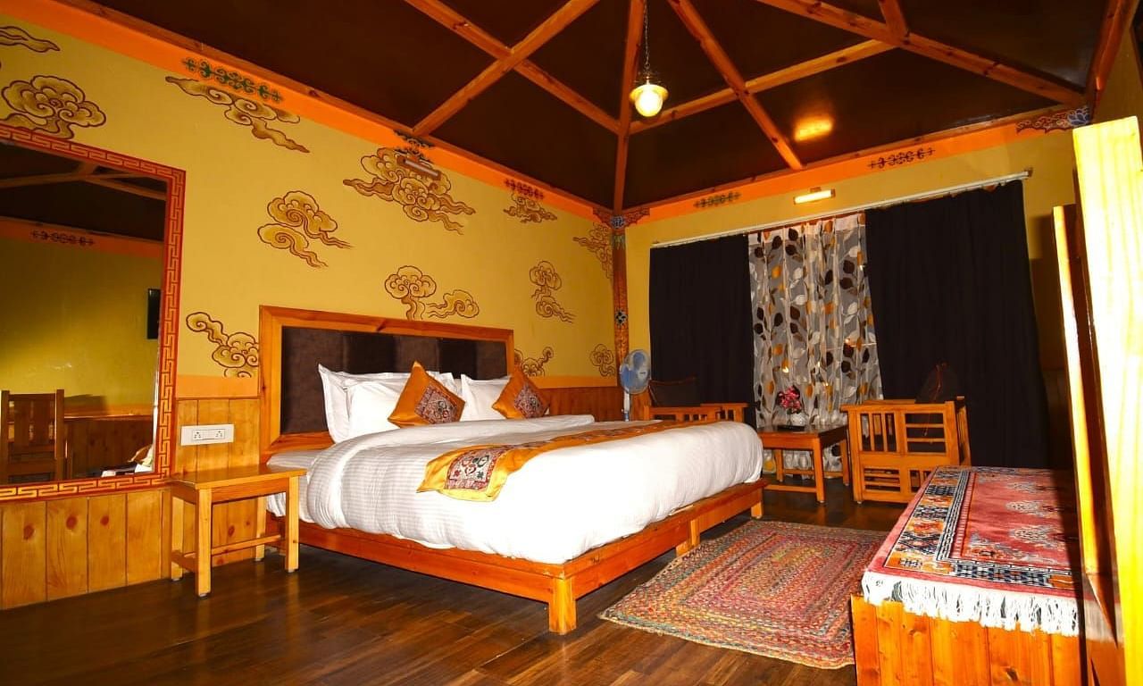 Premium Cottage at White Sands Resort, Ladakh, emphasising the king size bed, wooden furniture, and a rug.