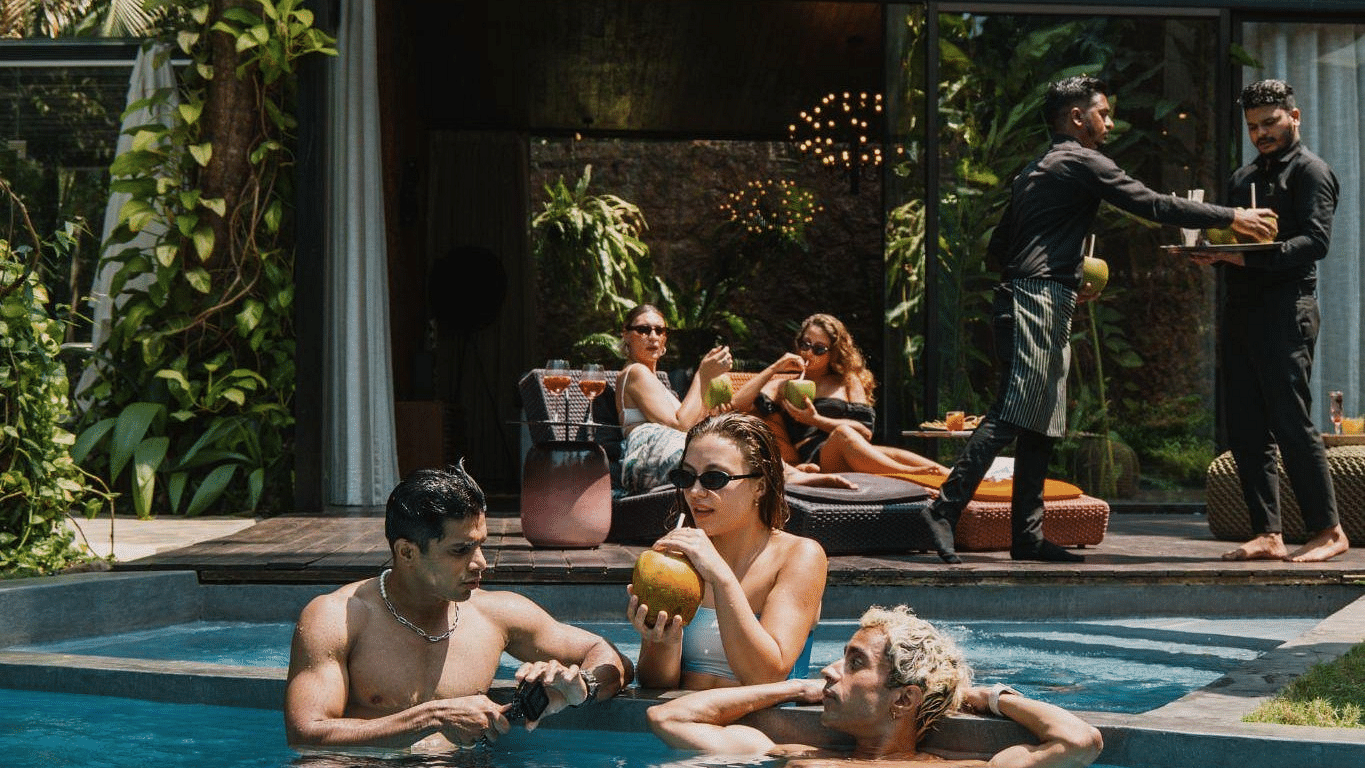 People chilling in the swimming pool under the sun while the rest are relaxing on the deck in the background