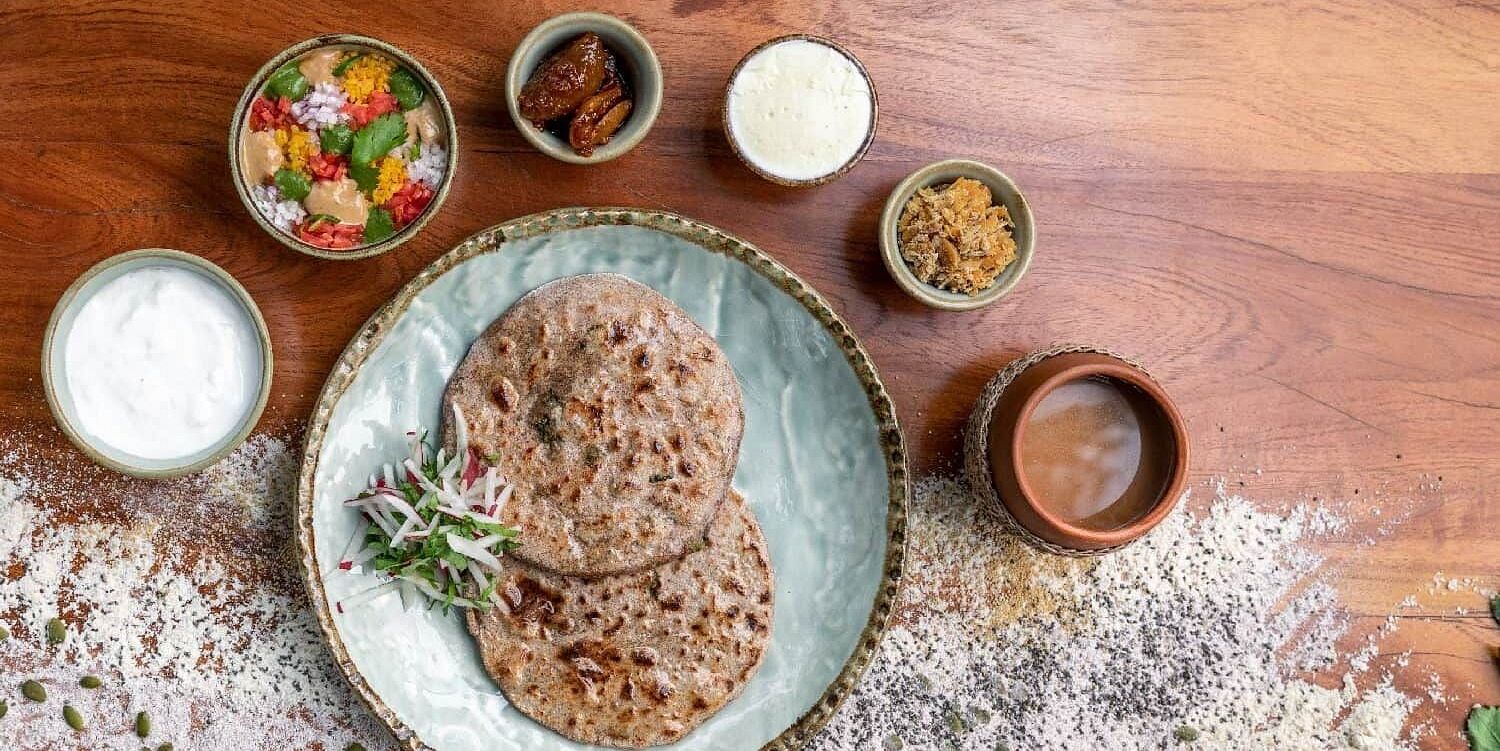 Indian meal with roti, sauces, and vegetables on a wooden table at Karma Chalets.