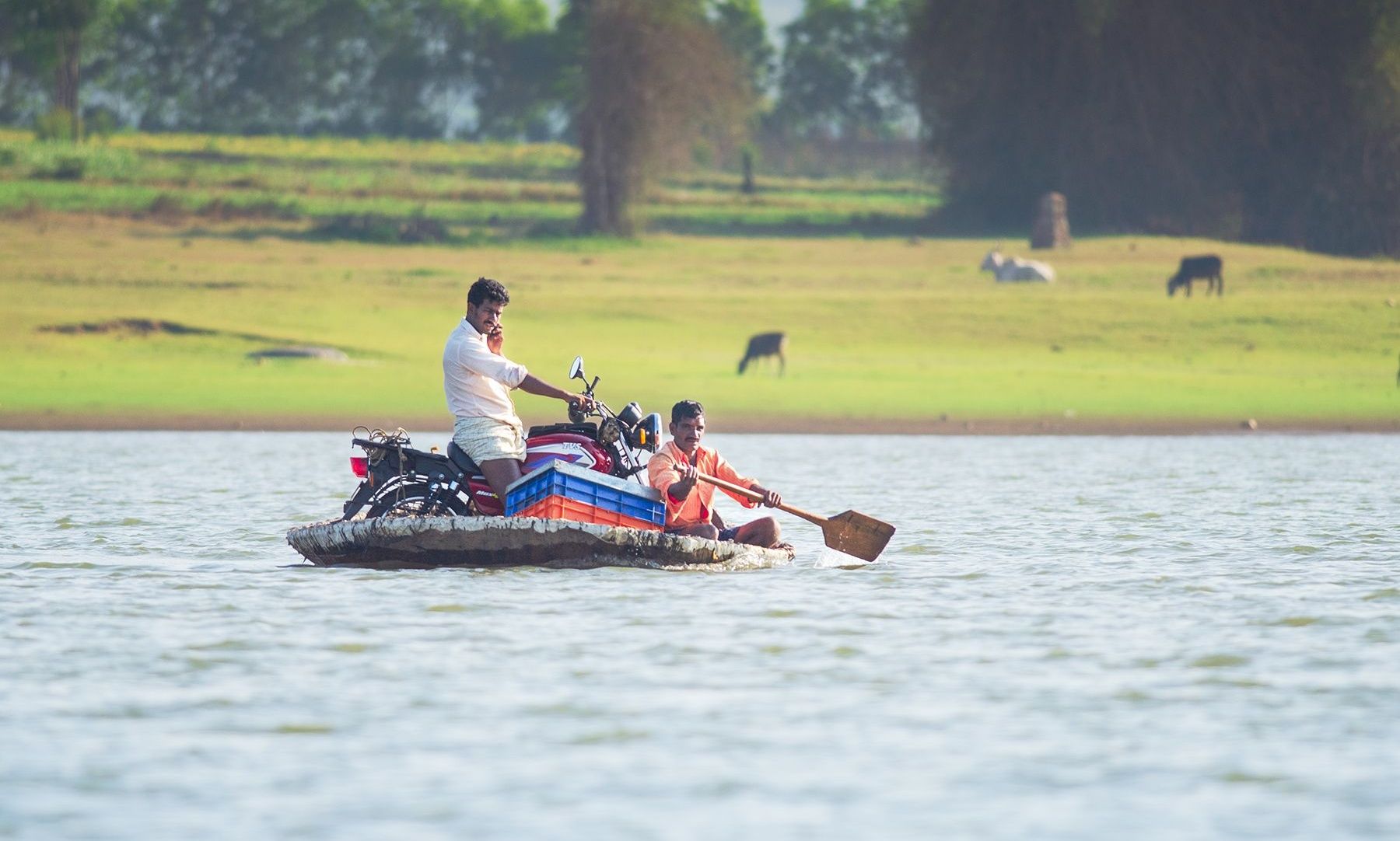 Two men on a makeshift raft rowing across water.