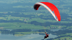 A man paragliding with a scenic view of lush green mountains and lake