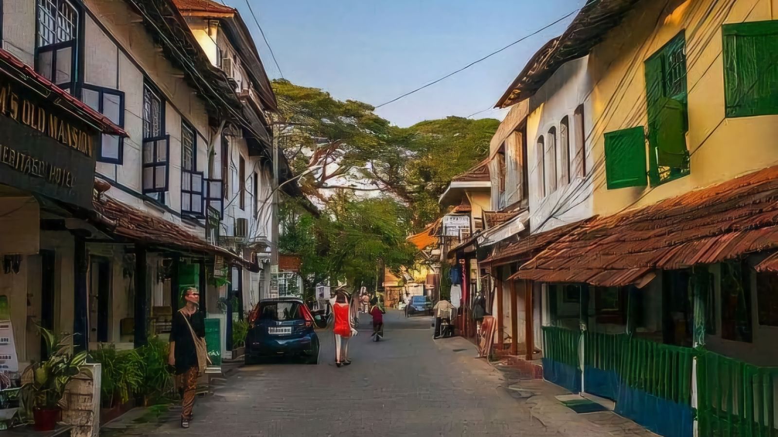 Narrow lane in Jew Town with old shops, wooden balconies, and people walking through.
