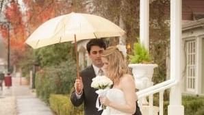 A groom holding an umbrella over a bride, walking down the stairs at Tallman Hotel.