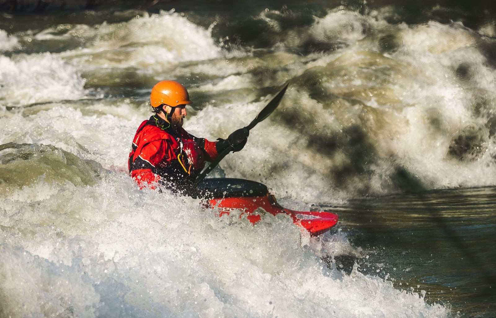 A person paddling in a bright red raft on a rushing river, doing an adventurous rafting experience.