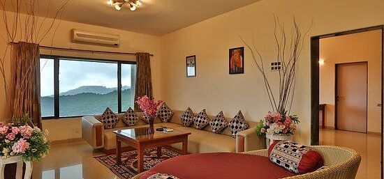 Image of living room of  a Pent House with a large window and spacious sofas - Camel Valley Resort, Igatpuri