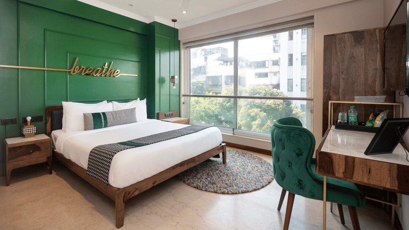 Deluxe Room featuring a plush bed facing the wall-mounted TV with a work desk below, offering a serene stay in Bandra at Theory9 - Premium Service Apartments