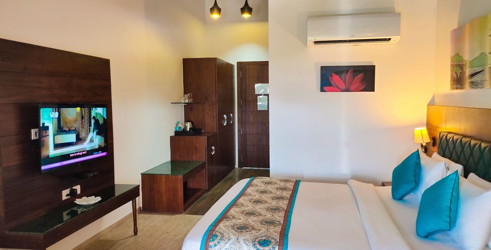 A bright, modern hotel room with a TV, bed with pillows, and a patterned runner. - Bamboo Saa Resort & Spa, Udaipur