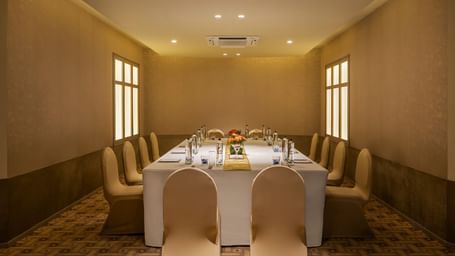  A meeting room at Shilton International, Kochi with a long table surrounded by chairs, set for a formal gathering.