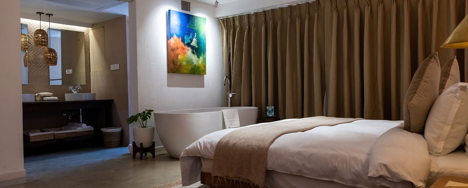 A spacious room with bed, bathtub, wall hanging and the washroom area at the Nepali Suite - The Nanee